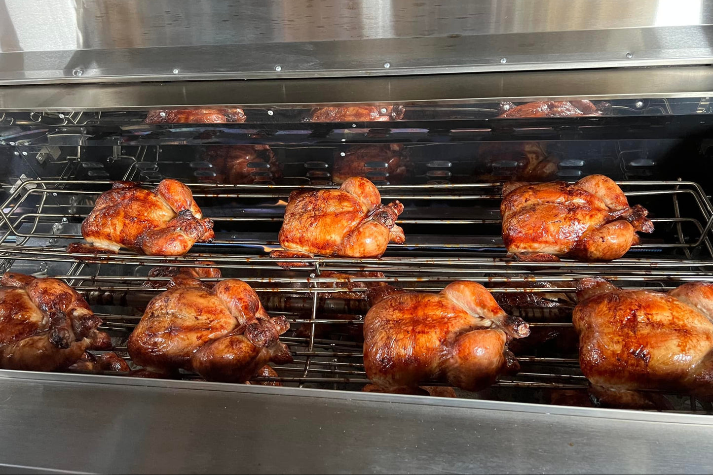 Roasted chickens on a grill rack inside an oven.